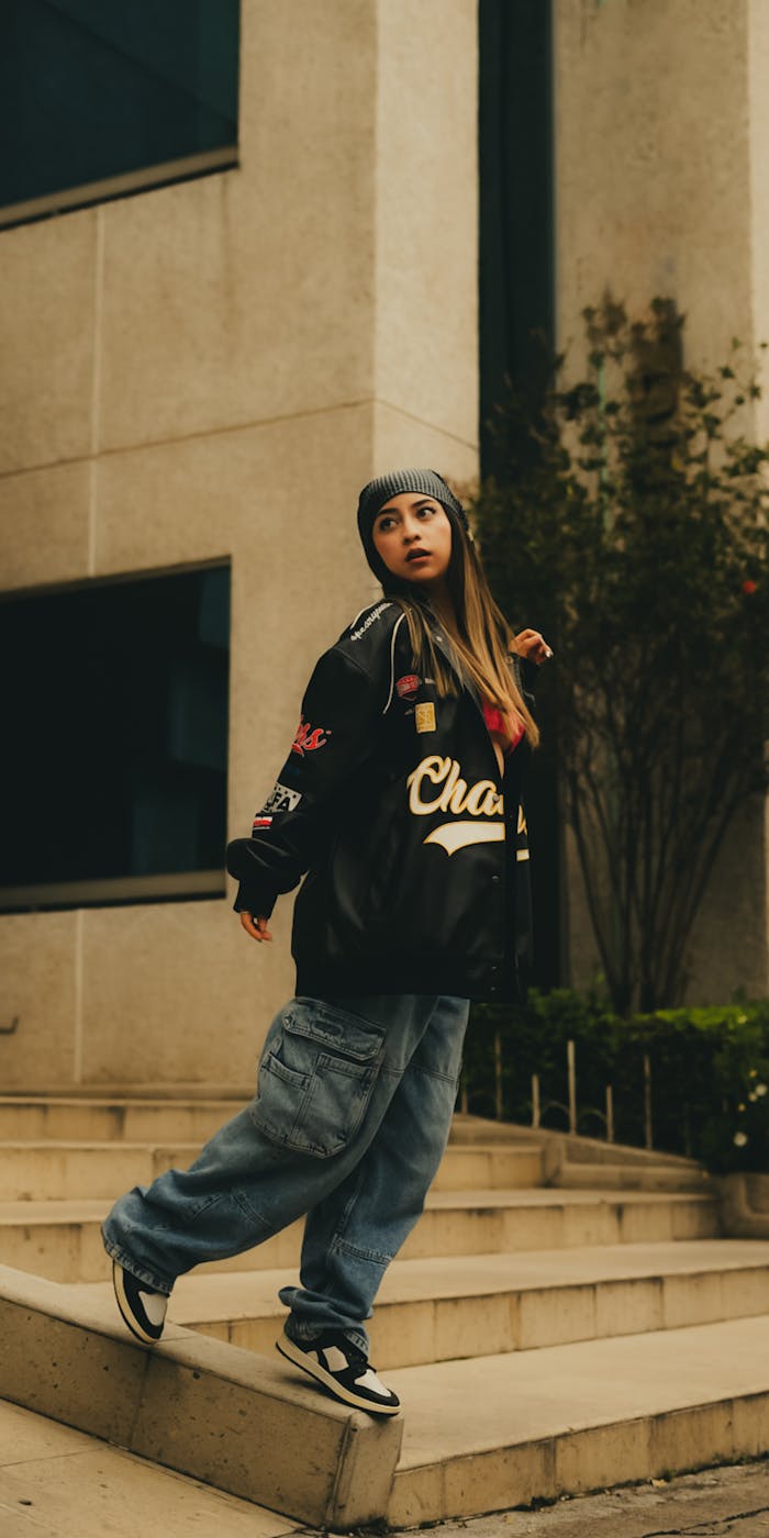 about-img Stylish woman in streetwear poses confidently on urban steps, showcasing modern fashion.